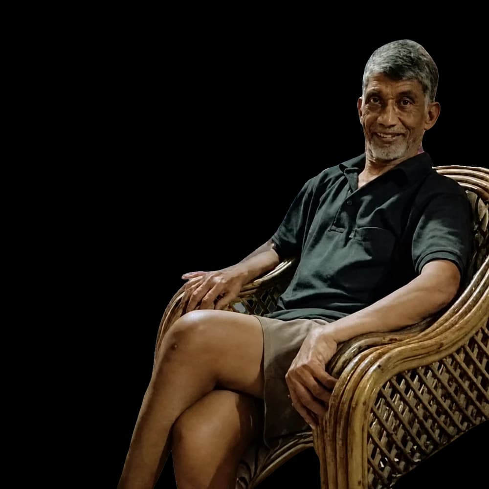 An older man seated in a wicker chair.
