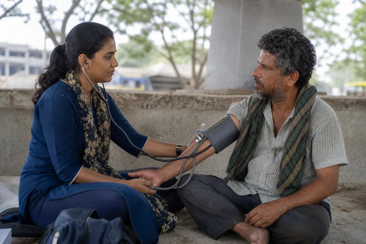A clinician checking a seated man's blood pressure at a community outreach table.